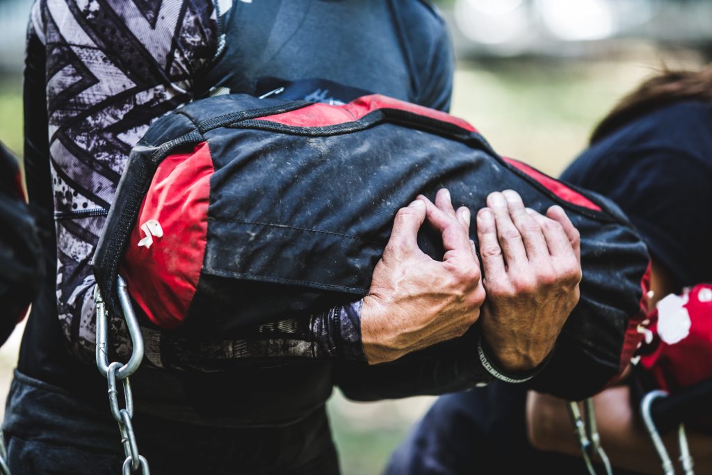 Close-up of man training at crossfit center with sandbag