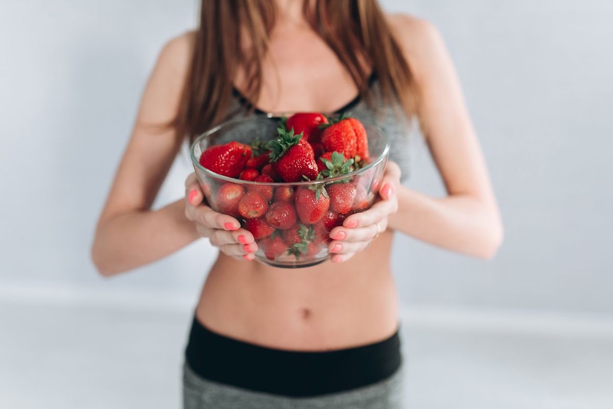 Fitness girl holding strawberries