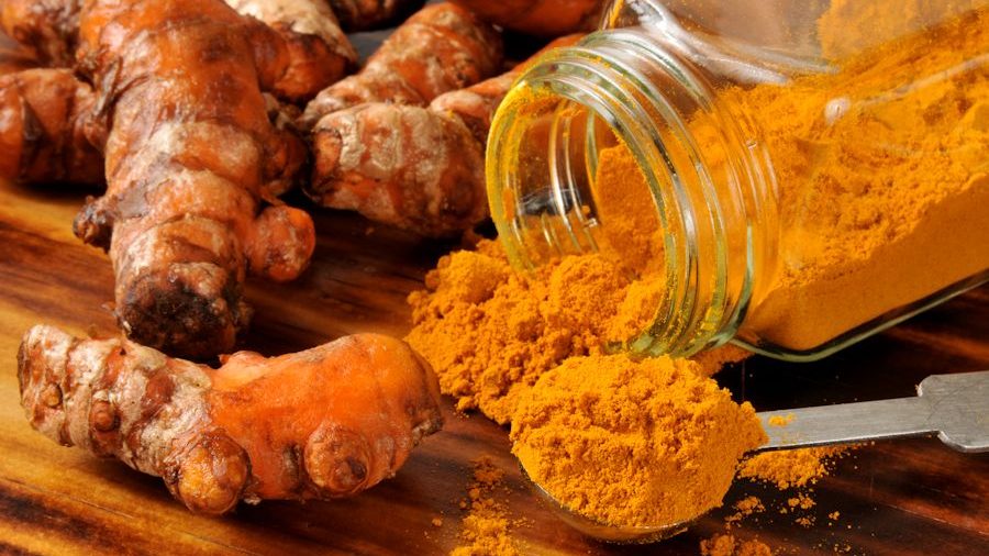 fresh turmeric and spice in a jar and spoon