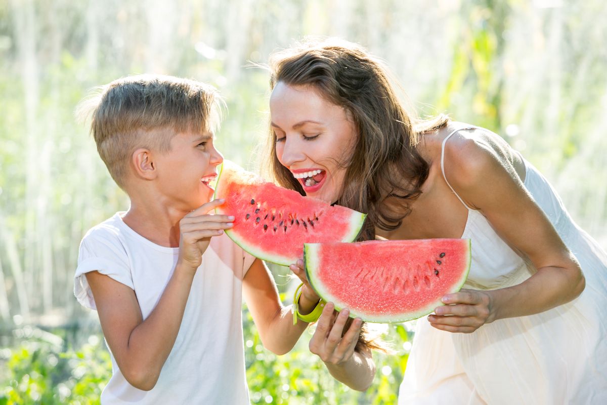 Happy smiling family eating watermelon on a sunny summer day